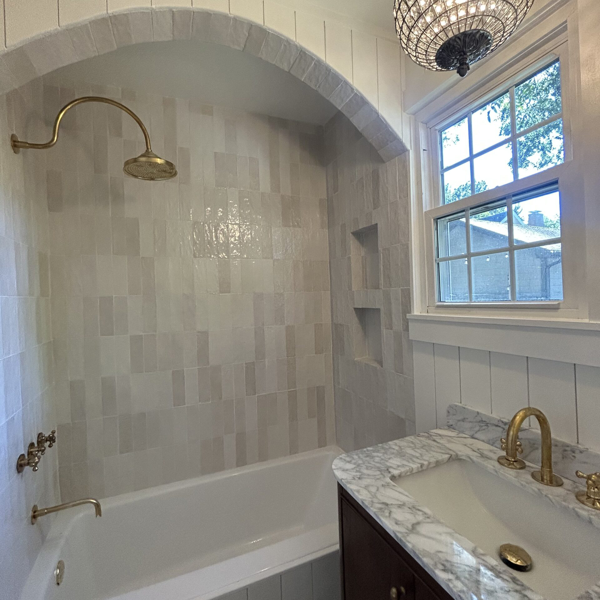 Luxury bathroom remodel with arched tile shower and marble vanity
